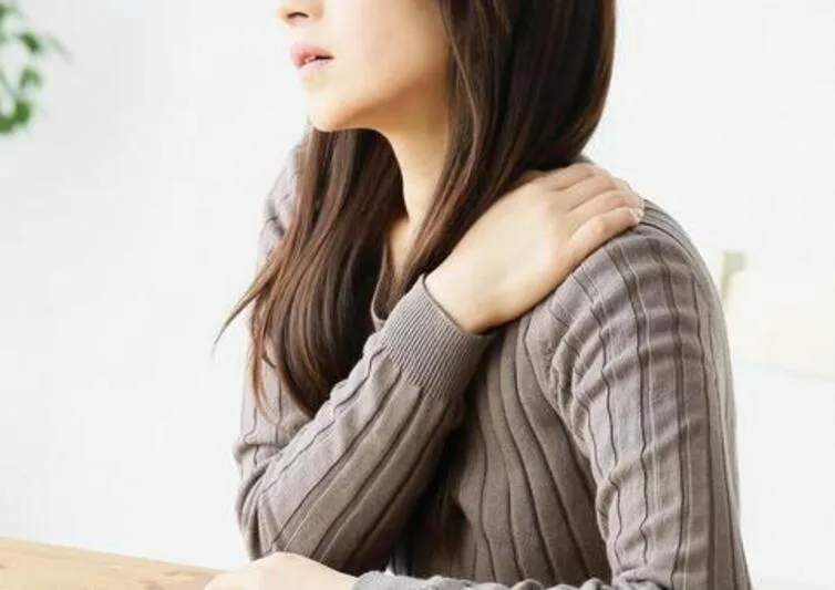 肩をおさえる女性